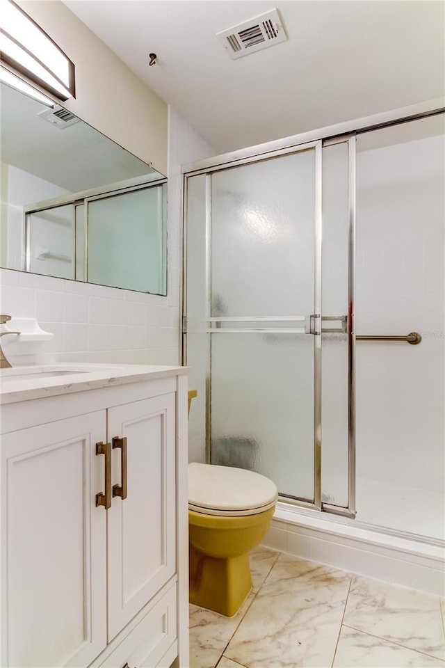 bathroom with vanity, toilet, tile walls, tasteful backsplash, and a shower with shower door