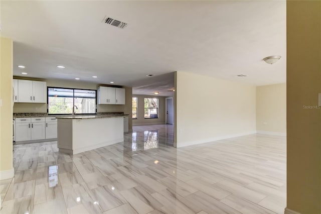 kitchen with white cabinets, a center island, plenty of natural light, and sink