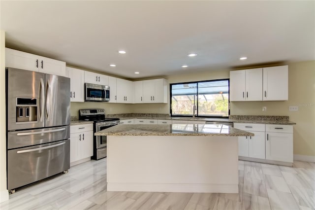 kitchen with light stone countertops, white cabinetry, a center island, stainless steel appliances, and sink