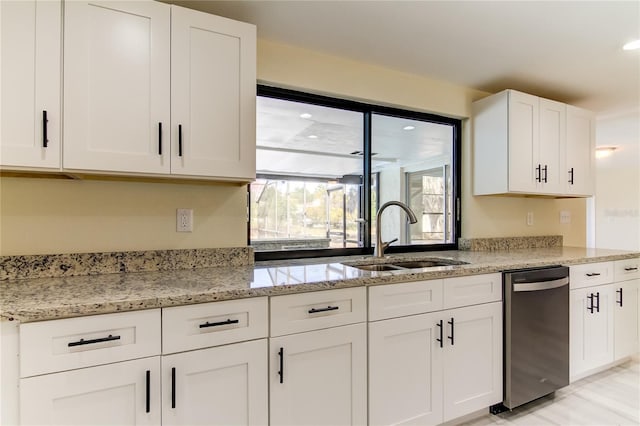 kitchen featuring white cabinets, stainless steel dishwasher, light stone countertops, and sink