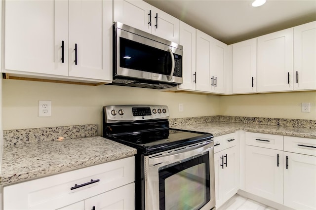 kitchen with white cabinets, stainless steel appliances, and light stone counters