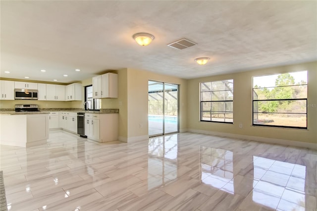 kitchen with a wealth of natural light, white cabinetry, sink, and appliances with stainless steel finishes