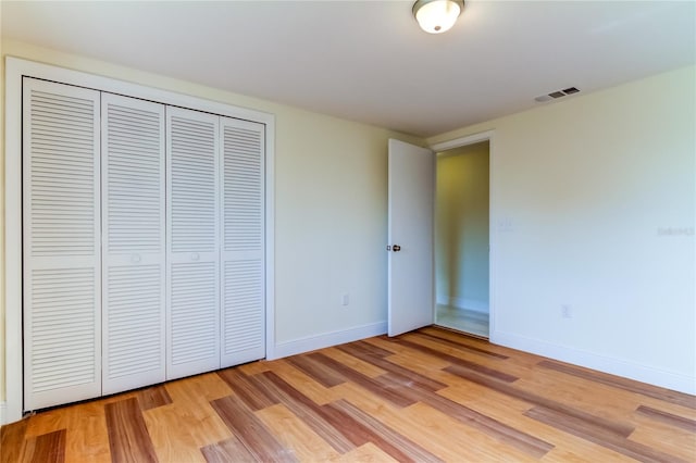 unfurnished bedroom with light wood-type flooring and a closet