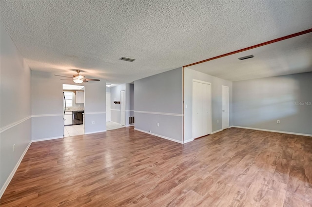 unfurnished living room featuring a textured ceiling, hardwood / wood-style flooring, and ceiling fan