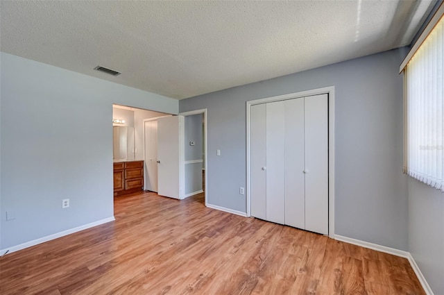 unfurnished bedroom with multiple windows, a closet, a textured ceiling, and light hardwood / wood-style flooring