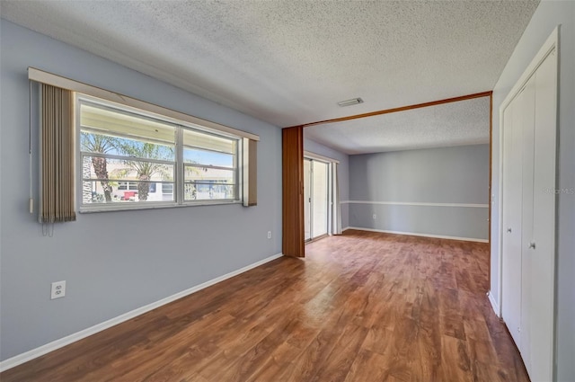 empty room with dark hardwood / wood-style floors and a textured ceiling