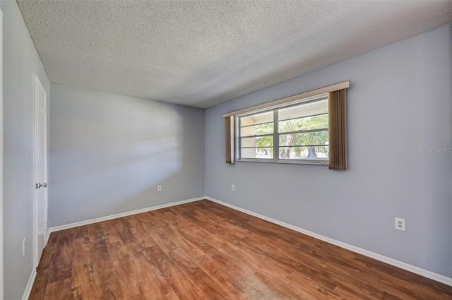 empty room featuring wood-type flooring and a textured ceiling