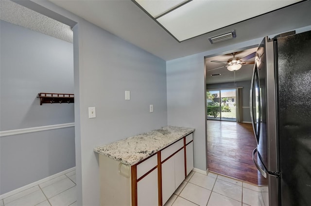 kitchen with white cabinets, stainless steel fridge, light tile patterned floors, and ceiling fan