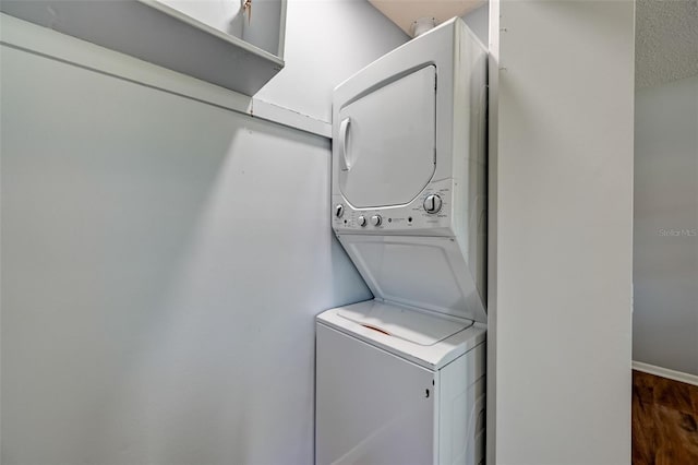 laundry room featuring a textured ceiling, stacked washing maching and dryer, and dark wood-type flooring