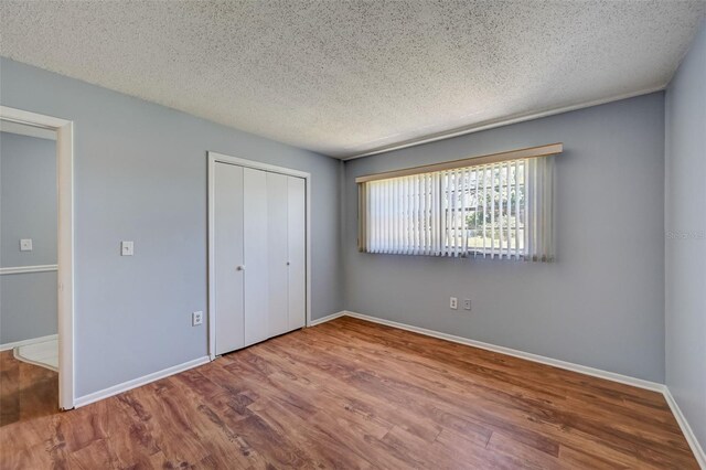 unfurnished bedroom featuring a closet, wood-type flooring, and a textured ceiling