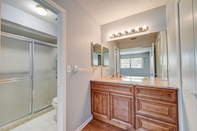 bathroom featuring vanity, a shower with shower door, a textured ceiling, and toilet