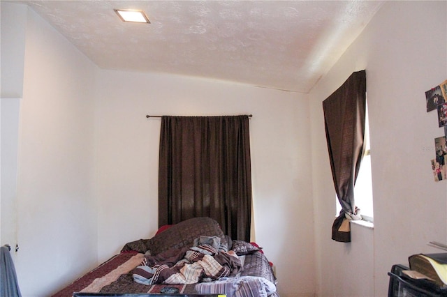 bedroom featuring lofted ceiling and a textured ceiling