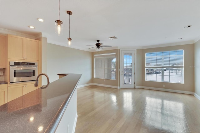 kitchen featuring hanging light fixtures, stainless steel oven, ornamental molding, and light hardwood / wood-style flooring