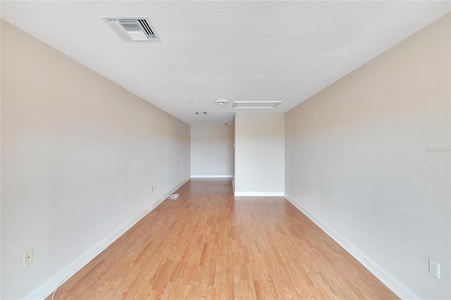 unfurnished room featuring a textured ceiling and light hardwood / wood-style flooring