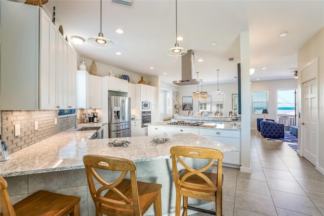 kitchen with kitchen peninsula, appliances with stainless steel finishes, white cabinets, and a breakfast bar area