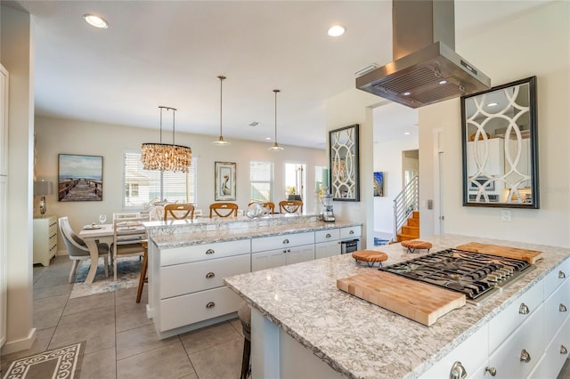 kitchen with white cabinetry, stainless steel gas cooktop, a breakfast bar area, island range hood, and a kitchen island