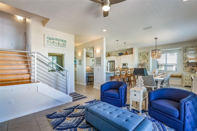 tiled living room featuring ceiling fan with notable chandelier