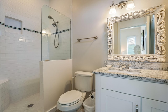 bathroom featuring tiled shower, vanity, and toilet