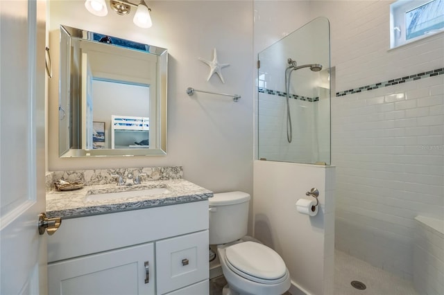 bathroom with vanity, toilet, and a tile shower