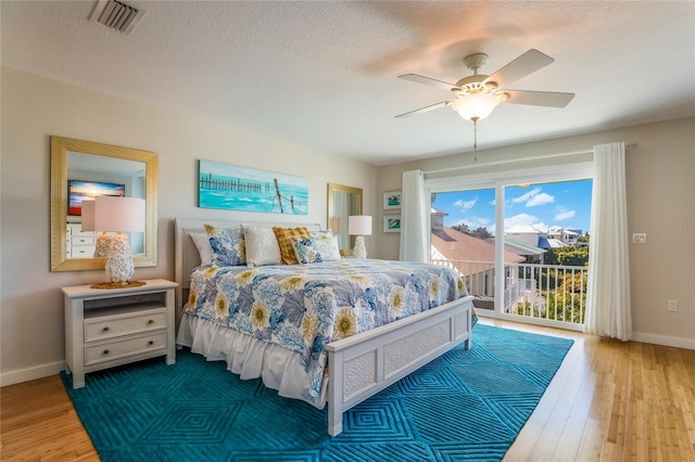 bedroom with access to exterior, ceiling fan, hardwood / wood-style floors, and a textured ceiling