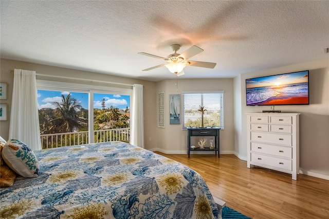 bedroom with access to outside, ceiling fan, light hardwood / wood-style floors, and a textured ceiling