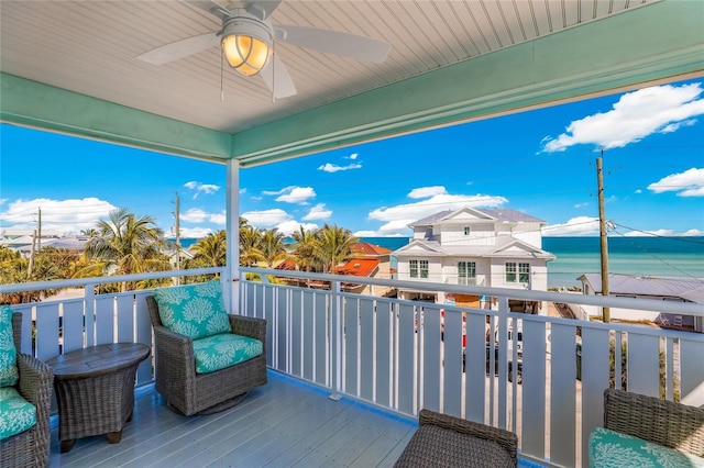 wooden deck with ceiling fan and a water view