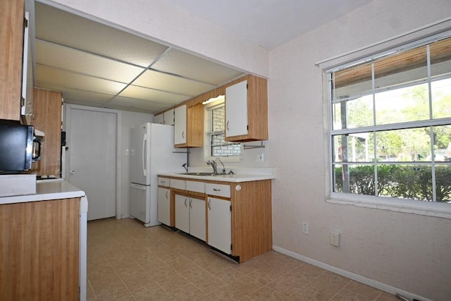 kitchen featuring sink, white cabinetry, light tile flooring, and white refrigerator