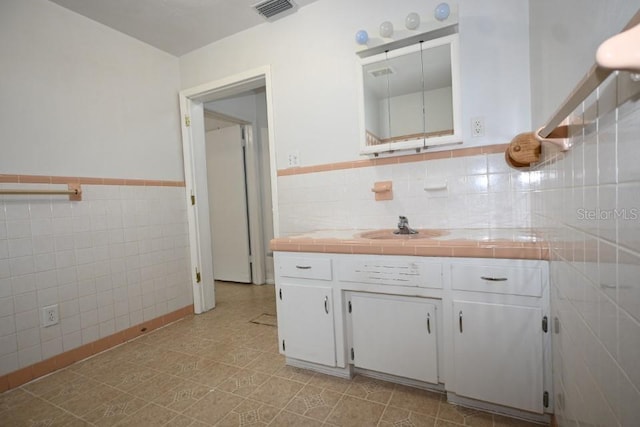 bathroom with tile walls, tile floors, vanity, and backsplash