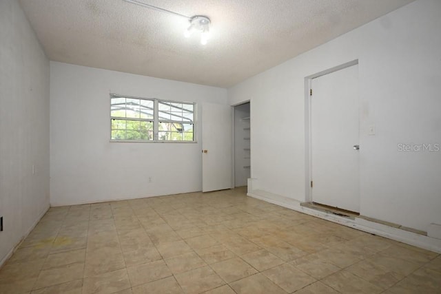 tiled spare room featuring a textured ceiling