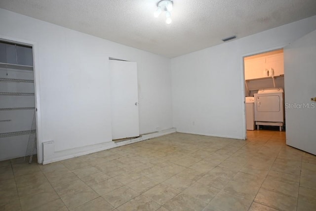 spare room featuring separate washer and dryer, light tile floors, and a textured ceiling