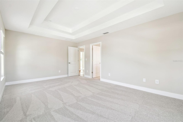 carpeted spare room featuring a tray ceiling