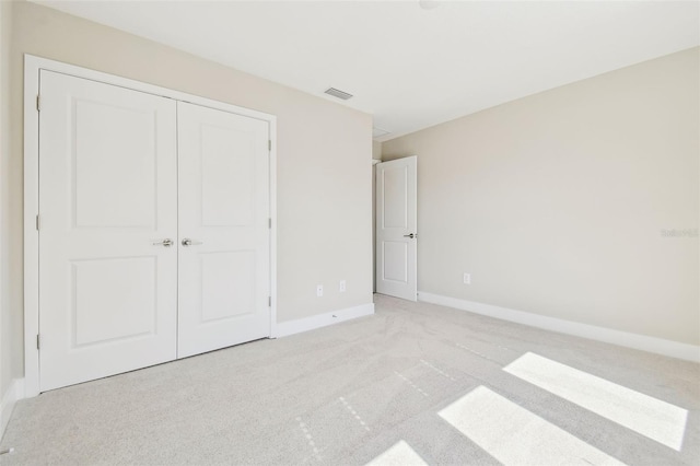 unfurnished bedroom featuring light carpet and a closet