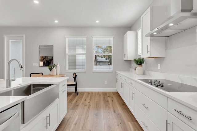 kitchen featuring dishwashing machine, white cabinetry, black electric cooktop, wall chimney exhaust hood, and light wood-type flooring