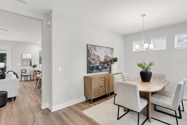 dining space with a notable chandelier and light hardwood / wood-style floors