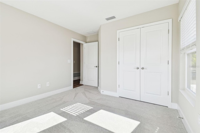 unfurnished bedroom featuring light carpet and a closet