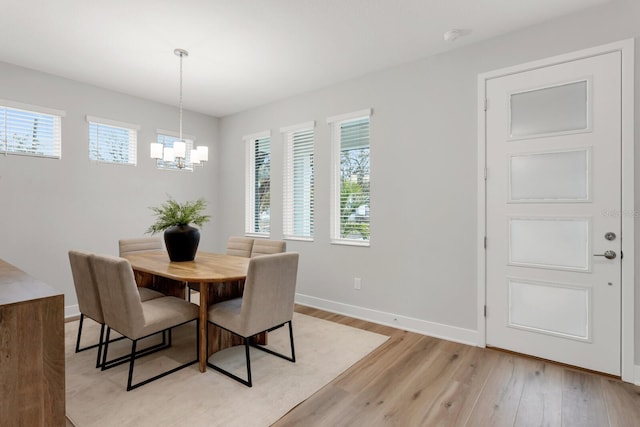 dining area with light hardwood / wood-style floors and a notable chandelier