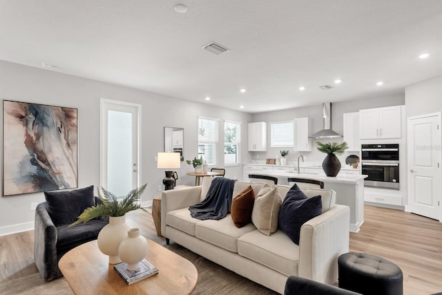 living room featuring sink and light hardwood / wood-style flooring