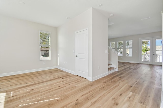 spare room with french doors and light hardwood / wood-style flooring