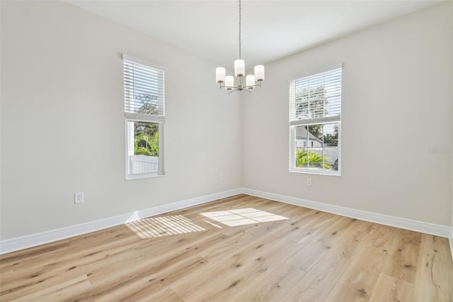 unfurnished room with light wood-type flooring and an inviting chandelier