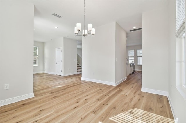 unfurnished dining area with light wood-type flooring and an inviting chandelier