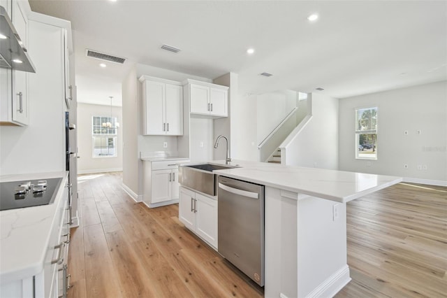 kitchen featuring white cabinets, stainless steel dishwasher, black electric cooktop, and a kitchen island with sink