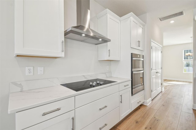 kitchen with wall chimney exhaust hood, black electric stovetop, stainless steel double oven, and white cabinetry