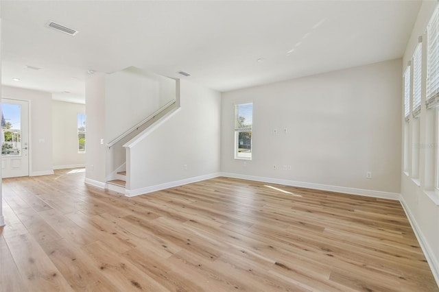 unfurnished living room featuring a wealth of natural light and light hardwood / wood-style flooring