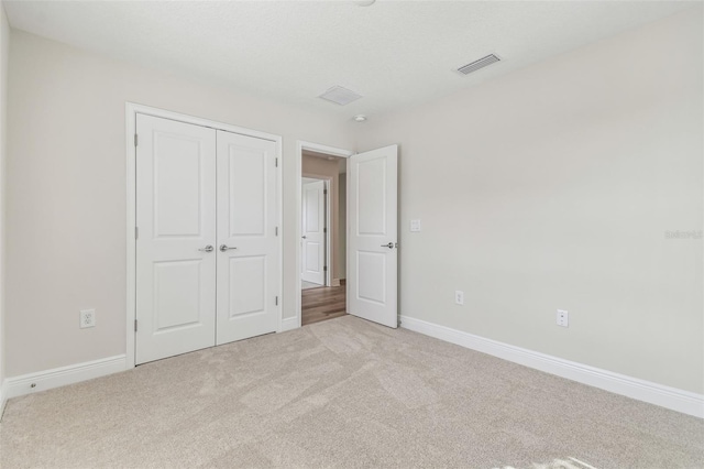 unfurnished bedroom featuring a closet and light colored carpet