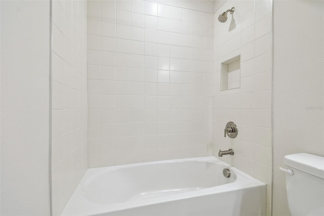 bathroom with tiled shower / bath combo and toilet