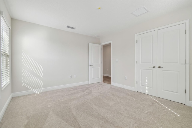 unfurnished bedroom with light carpet, multiple windows, and a closet