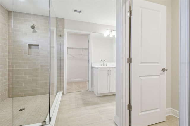 bathroom featuring tiled shower, tile patterned floors, and vanity