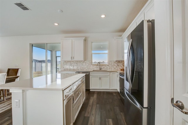 kitchen with white cabinetry, backsplash, sink, and stainless steel appliances