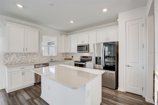 kitchen with backsplash, dark hardwood / wood-style floors, appliances with stainless steel finishes, white cabinets, and a center island