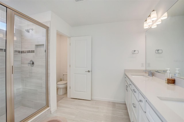 bathroom featuring toilet, a shower with shower door, oversized vanity, dual sinks, and tile floors